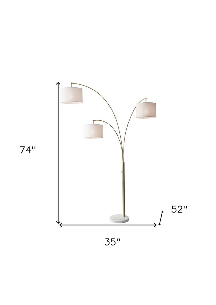 74" Brass Three Light Arc Floor Lamp With Off White Fabric Drum Shade